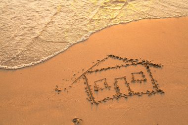 Conceptual photo: a house painted on beach sand