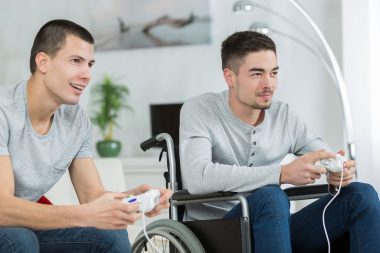 happy young brothers playing video games one is handicaped